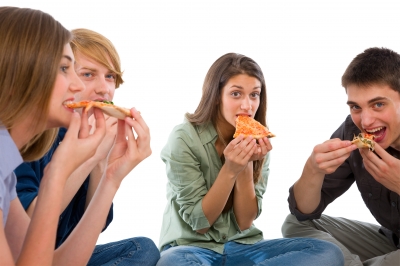 2 lány és 2 fiú kézzel esznek pizzát, törökülésben, körben ülve